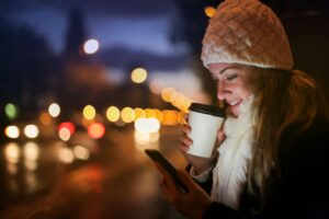 Woman on her phone with coffee.