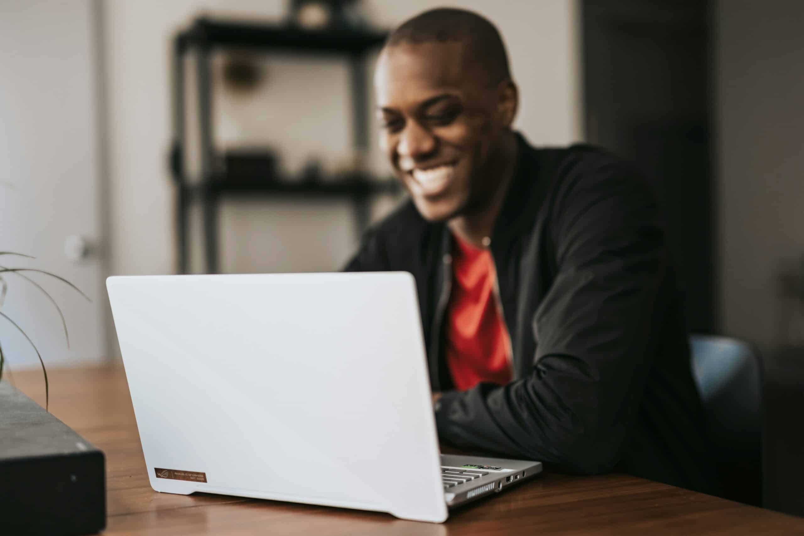 Man Smiling While Working on Laptop
